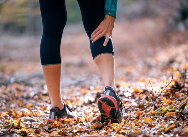 Sporty woman has muscle injury and holding her painful leg in th Close-up of sporty woman has muscle injury and holding her painful leg in the forest.