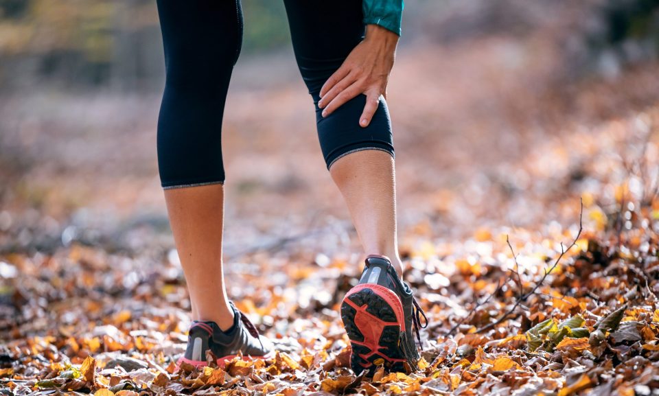 Sporty woman has muscle injury and holding her painful leg in th Close-up of sporty woman has muscle injury and holding her painful leg in the forest.