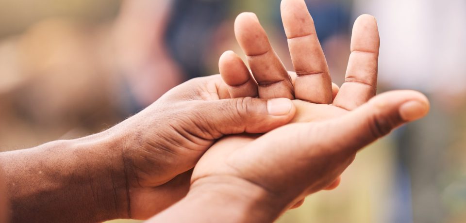Mano, lesión y hombre mayor con maqueta de artritis, inflamación y fractura sobre un fondo desenfocado.
