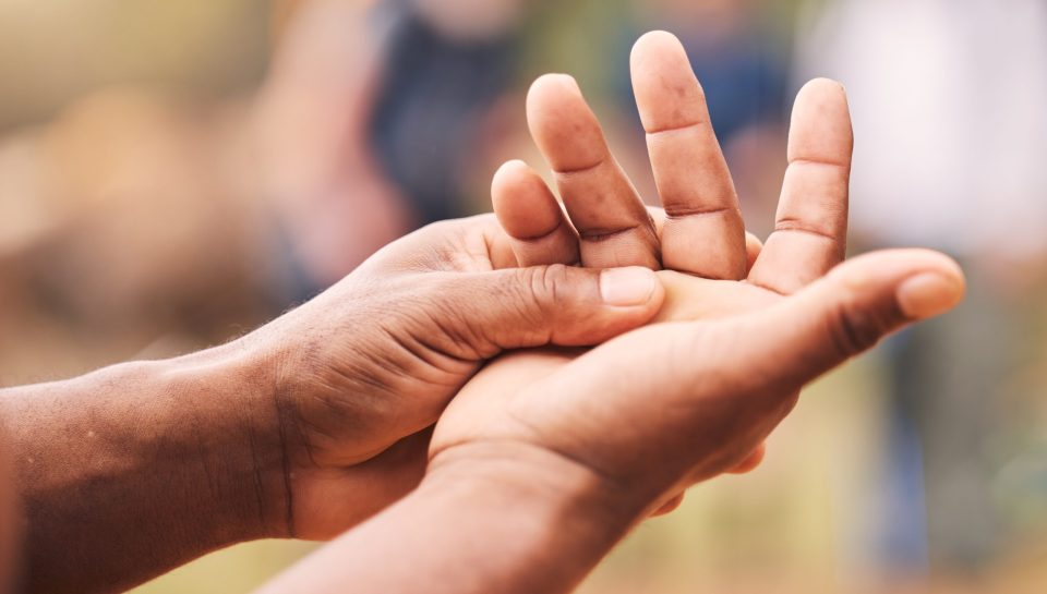Mano, lesión y hombre mayor con maqueta de artritis, inflamación y fractura sobre un fondo desenfocado.