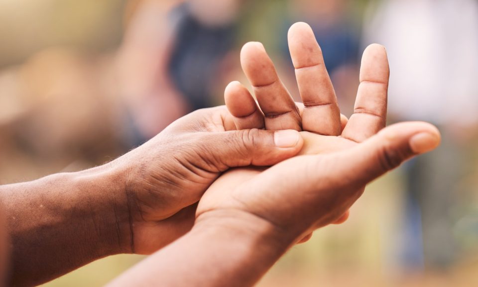 Mano, lesión y hombre mayor con maqueta de artritis, inflamación y fractura sobre un fondo desenfocado.